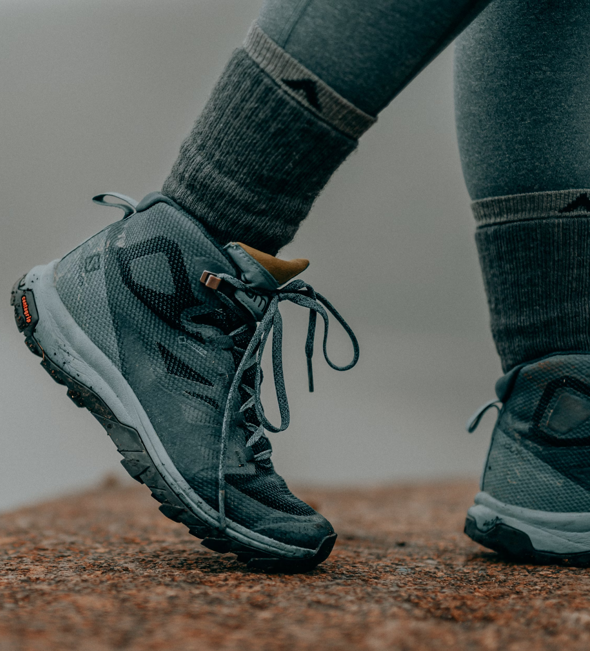 A person walking outside with merino wool socks on the ground.