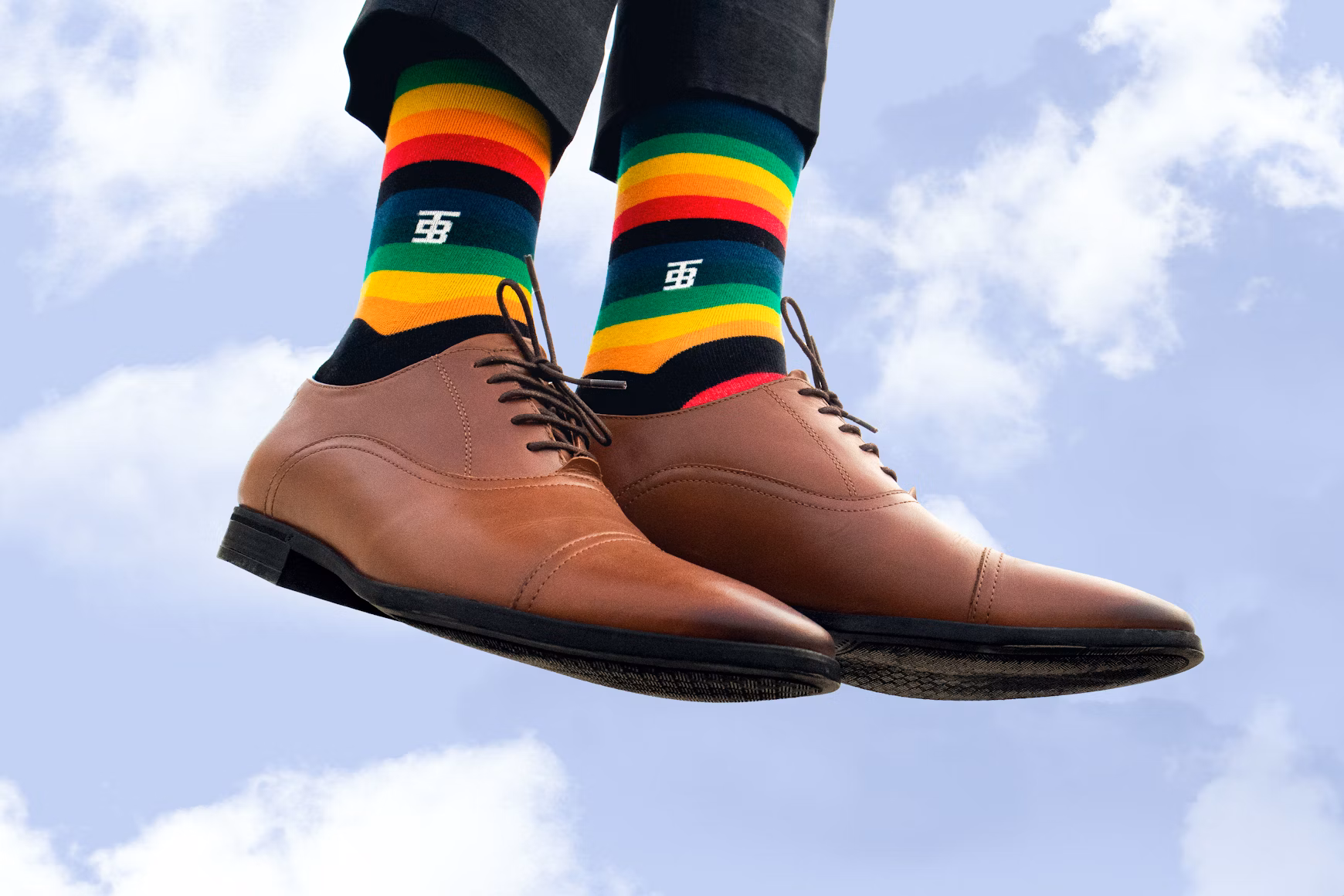 A person wearing a pair of striped dress socks and brown shoes