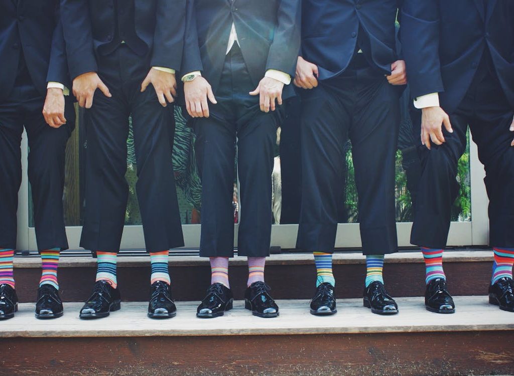A fun group of men in formal suits showing off colorful dress socks