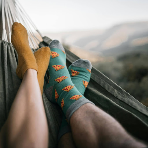 Two people’s feet with socks on laying in a hammock