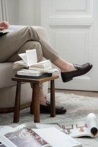 Man's leg wearing loafers next to a book on a small table